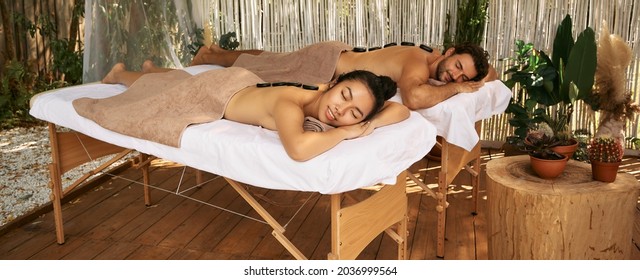 Beautiful couple during hot stone massage therapy, joint day at wellness spa, outdoors - Powered by Shutterstock