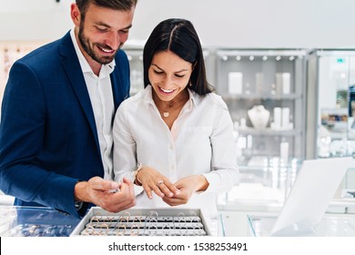 Beautiful Couple Enjoying In Shopping At Modern Jewelry Store. Close Up Shot Of Woman's Hand With Gorgeous Expensive Ring And Bracelet.