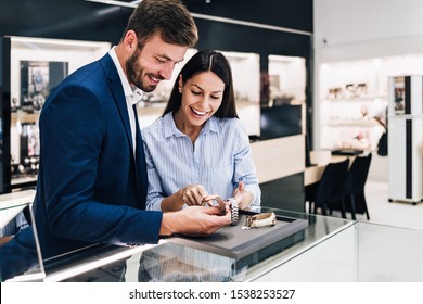 Beautiful Couple Enjoying In Shopping At Modern Jewelry Store. Close Up Shot Of Human Hand Holding Expensive Watch.