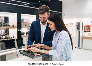 Beautiful Couple Enjoying In Shopping At Modern Jewelry Store. Close Up Shot Of Human Hand Holding Expensive Watch.