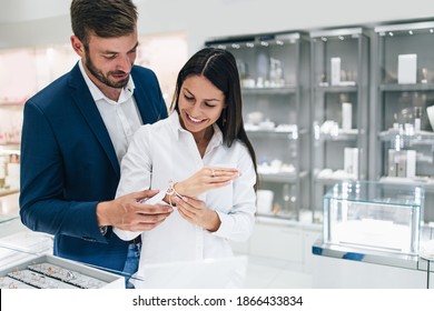 Beautiful Couple Enjoying In Shopping At Modern Jewelry Store. Close Up Shot Of Woman's Hand With Gorgeous Expensive Ring And Bracelet.