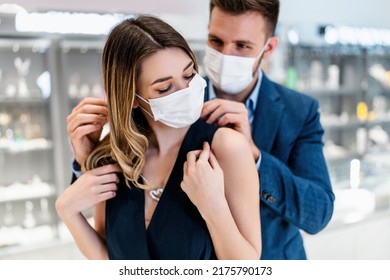 Beautiful couple with face protective masks enjoying in shopping at modern jewelry store. Young woman try it out gorgeous necklace and earrings. Fashion style and elegance concept. Pandemic lifestyle. - Powered by Shutterstock