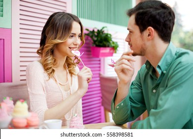 Beautiful  couple having fun licking heart lollipops on their first date