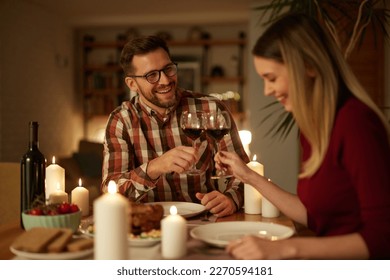 Beautiful couple having romantic dinner with candles and red wine at home - Powered by Shutterstock