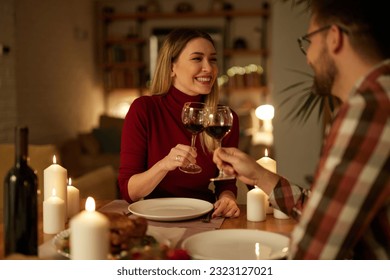 Beautiful couple having romantic dinner with candles and red wine at home - Powered by Shutterstock