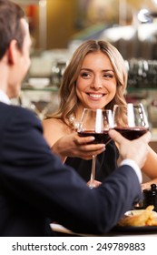 Beautiful couple having romantic dinner at restaurant. smiling woman looking at man dinking wine at toast