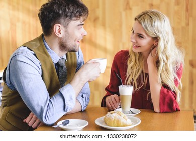 beautiful couple holding coffee cups and looking at each other 