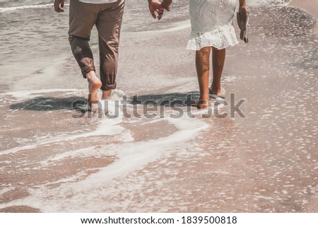 Beautiful couple holding hands on the beach walking