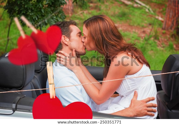Beautiful couple kissing in back seat against hearts\
hanging on a line