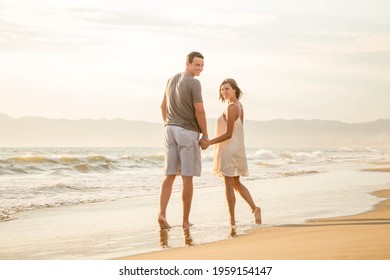 Beautiful couple kissing in a sun set beach with an amazing sky and clouds.