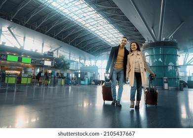 Beautiful couple in love enjoys a joint journey, walks through the departure-arrival hall, waits for customs and passport control at an international airport on the background of flight check-in board - Powered by Shutterstock