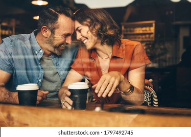 Beautiful couple in love having a coffee date. Loving couple sitting at cafe touching foreheads and smiling.