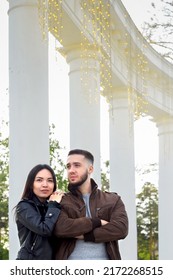 Beautiful Couple In Love On Romantic Dating In Summer City Park At Tall Columns, Sensual Relationship Of Young Man And Woman, Candid Lifestyle, Vertical Image