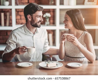 Beautiful couple in love is sitting in cafe, drinking coffee and eating cheesecake. Looking softly on each other. - Powered by Shutterstock