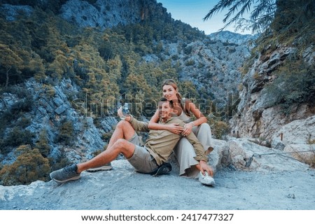 A beautiful couple, a man and a woman, took a break while hiking along the Lycian Way with the Goynuk Canyon in the background in Kemer, Antalya, Turkey.