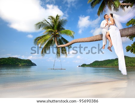 beautiful couple on the beach in wedding dress on palm tree