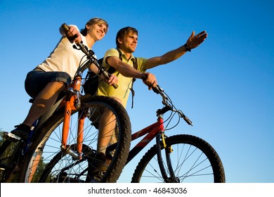 Beautiful Couple on bicycles on the brink of a rock and look afar from rock breakage