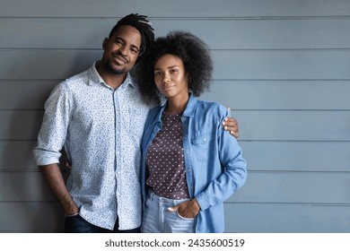 Beautiful couple pose on wooden blue wall studio background. African man with dreadlocks hug curly haired woman look at camera. Romantic relations, love, mixed race family half-length portrait concept - Powered by Shutterstock