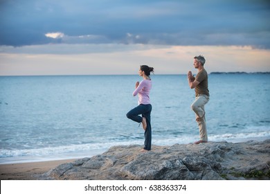 Beautiful couple practicing yoga on the beach at sunrise - Powered by Shutterstock