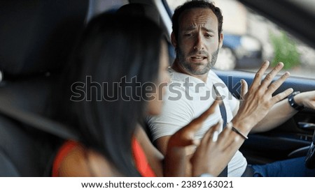 Beautiful couple sitting on car arguing at street