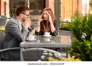 Beautiful couple sitting in restaurant, drinking coffee and arguing on sunny spring day - Powered by Shutterstock