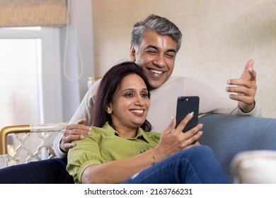  Beautiful Couple Spending Leisure Time Using Phone At Home