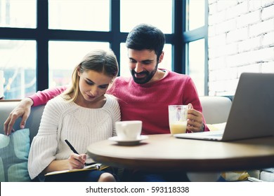 Beautiful couple of stylish hipster guys sitting in cozy coffe shop and spending time together having some tea in autumn day. Couple in love making planning list for weekend with things to do together