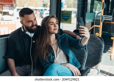 Beautiful couple taking selfie with a smartphone while riding the bus in the city - Powered by Shutterstock