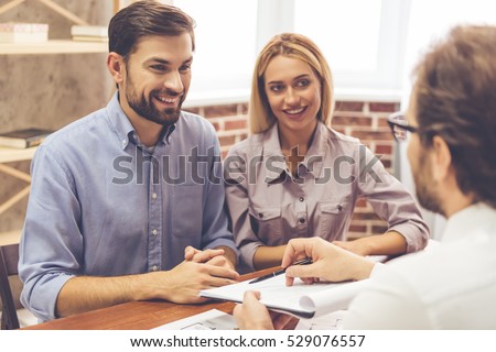 Beautiful couple is talking with realtor, who is showing where to sign the documents Stockfoto © 