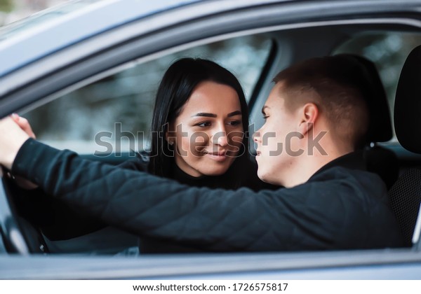 Beautiful couple talking and
smiling while sitting in their car. A happy young couple is
sitting. Travel and adventure concept. Traveling in comfort. Love
in the car.