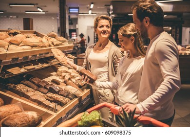 Beautiful couple and their daughter are smiling while doing shopping in supermarket - Powered by Shutterstock