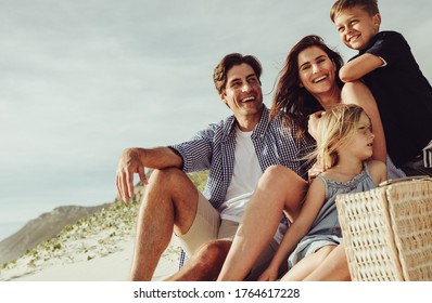 Beautiful couple with their son and daughter relaxing on the seashore on a summer day. Happy family sitting on the beach. - Powered by Shutterstock