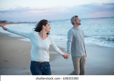 Beautiful couple walking on the beach at sunset. They are barefoot and wearing casual clothes - Powered by Shutterstock