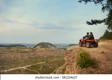Beautiful couple is watching the sunset from the mountain sitting on quadbike