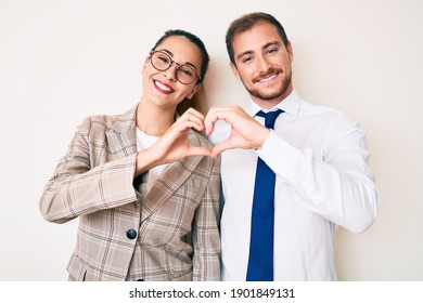 Beautiful Couple Wearing Business Clothes Smiling In Love Doing Heart Symbol Shape With Hands. Romantic Concept. 