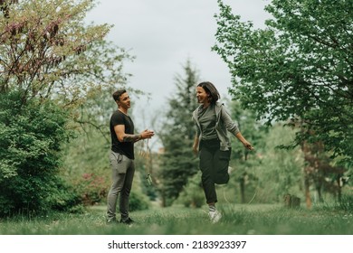 Beautiful couplehaving fun while jumping on the rope on the grass in the park