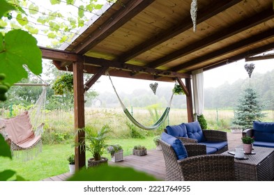 Beautiful covered terrace in the green garden with natural wood, rattan furniture, hammock. Summer outdoor and relax in patio.