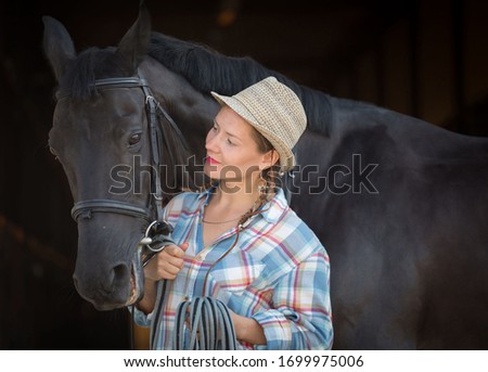 Beautiful cow girl embrace horse. Wearing a plaid shirt and hat. People and animal portrait. Horseback riding view. Amazing nature sport. Person hobby hippotherapy. 