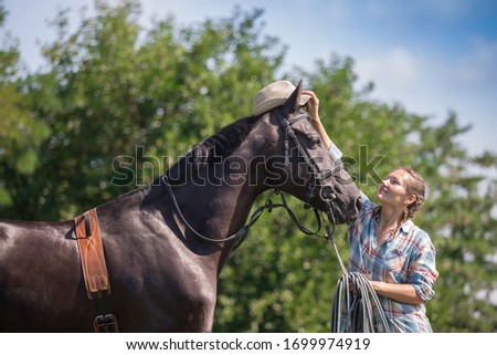Beautiful cow girl walking horse in green field. People and animal portrait. Horseback riding view. Amazing nature landscape. Person hobby hippotherapy.