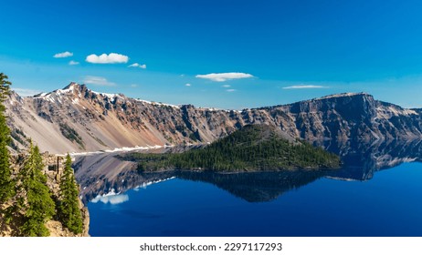 Beautiful Crater Lake National Park with late season snow still lingering into early summer. Bright blue lake with reflections - Shutterstock ID 2297117293
