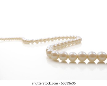 Beautiful creamy pearl necklace on a white reflective surface
