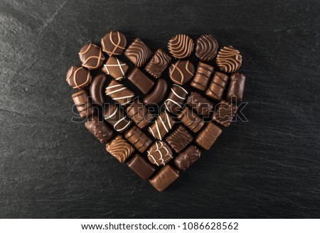 Beautiful Creative Chocolate Heart on Natural Black Stone Background. Mix of Chocolates Top View and Flat Lay with Place for Text