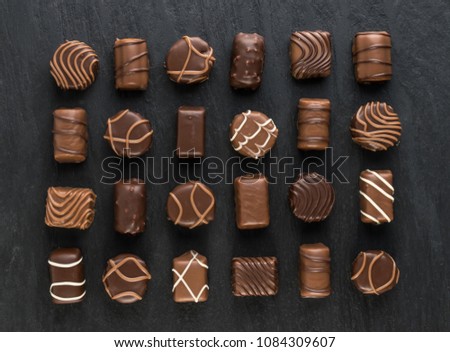 Beautiful Creative Chocolate Sweets on Natural Black Stone Background. Mix of Chocolates Top View and Flat Lay