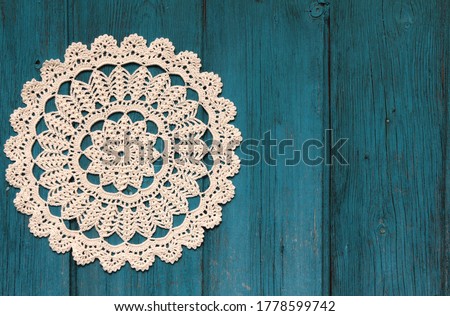 Beautiful crochet doily on blue wooden background
