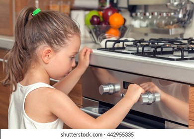 beautiful curious little girl examining oven in kitchen