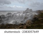 Beautiful and curious seascape seeing the northern rocky coast of Portugal covered with spray of a stormy wave that had just hit the cliffs