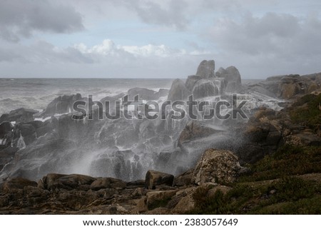 Beautiful and curious seascape seeing the northern rocky coast of Portugal covered with spray of a stormy wave that had just hit the cliffs