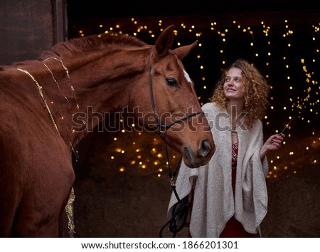 Beautiful curly girl with a red horse on a black background in New Year's decorations