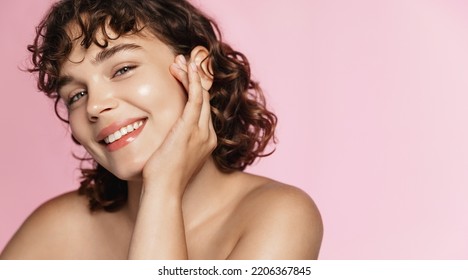 Beautiful curly girl smiles as she likes skincare effect after beauty gel. Portrait of young woman washing her face and body, pink background. - Shutterstock ID 2206367845