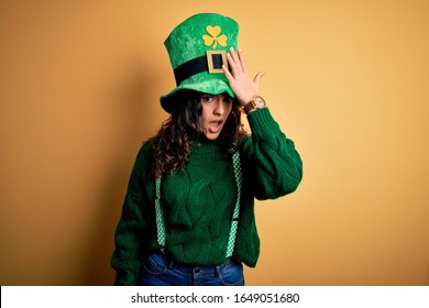 Beautiful Curly Hair Woman Wearing Green Hat With Clover Celebrating Saint Patricks Day Surprised With Hand On Head For Mistake, Remember Error. Forgot, Bad Memory Concept.